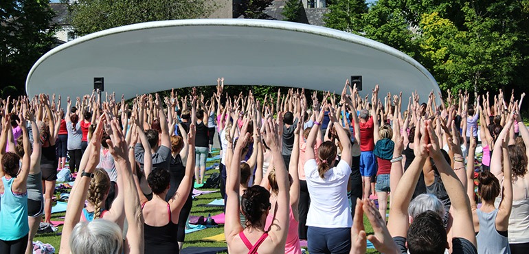 Lots of people practicing yoga in a park