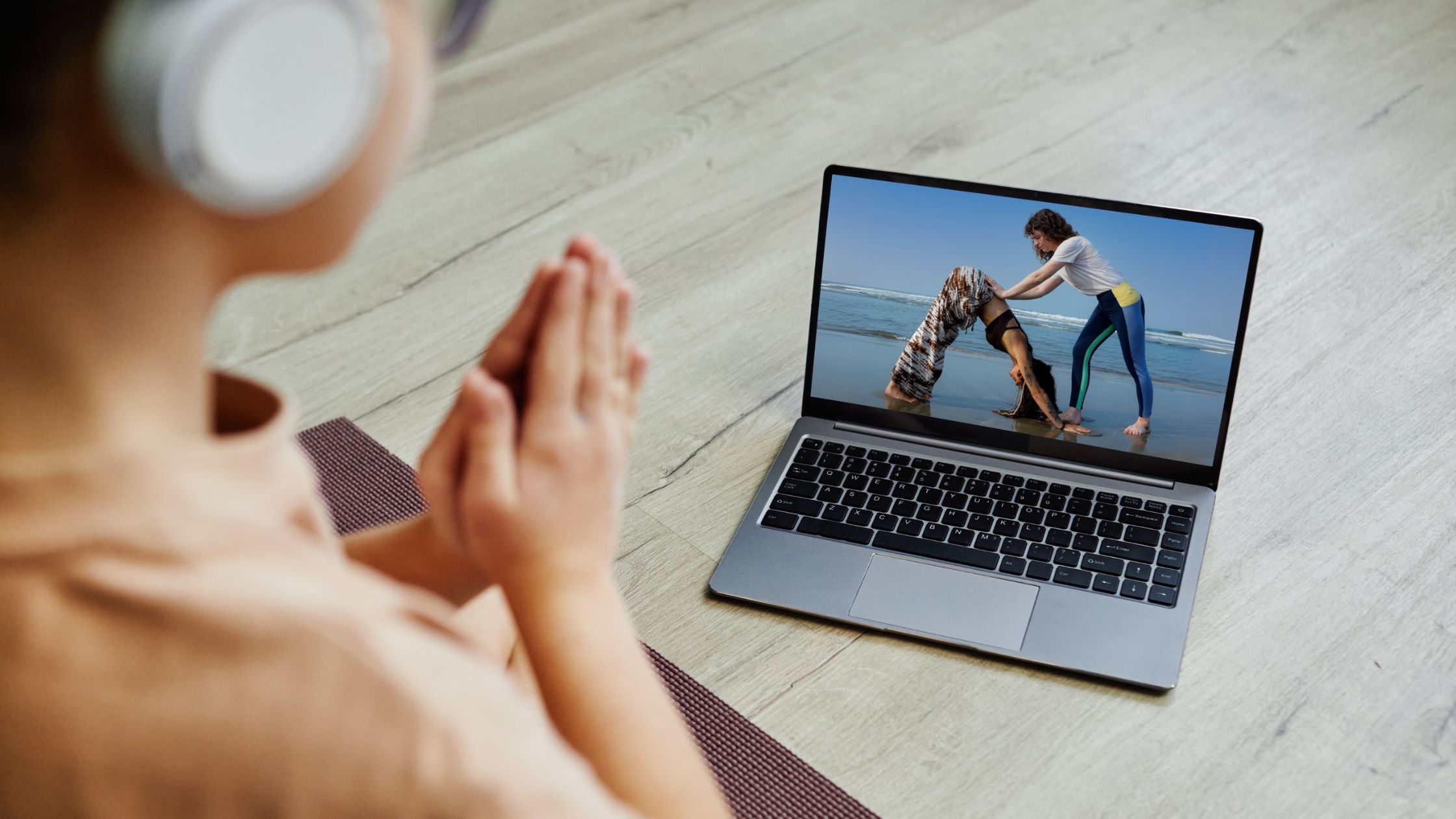 Student following an online yoga class on a laptop from home, engaged in yoga instructor online certification training