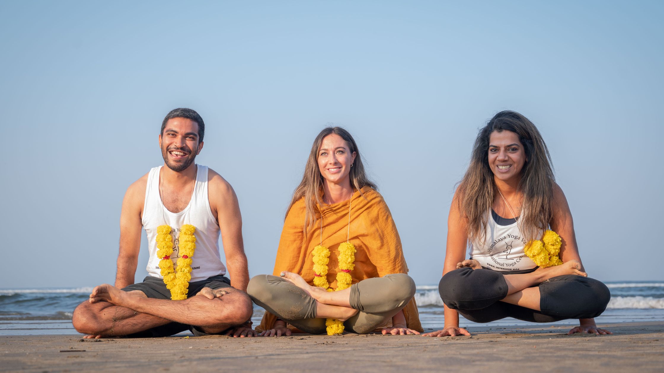 Group of students practising yoga at sunrise on the beach in Goa during teacher training